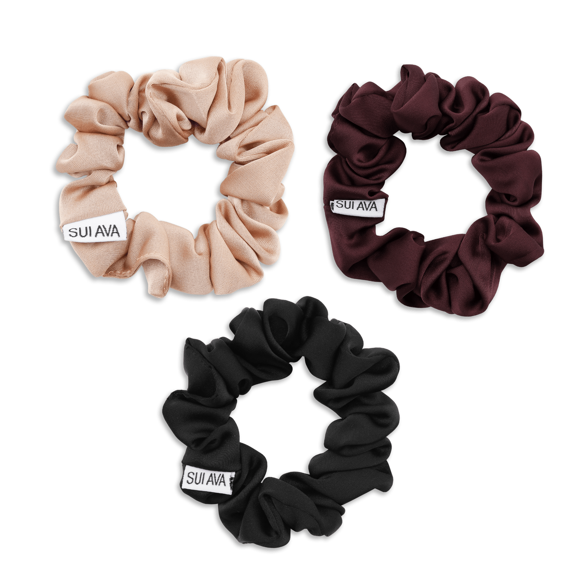 Tre ruched scrunchies fra SUI AVA i farverne mandel, sort og bordeaux – elegant hårpynt i blødt, rynket bånd.